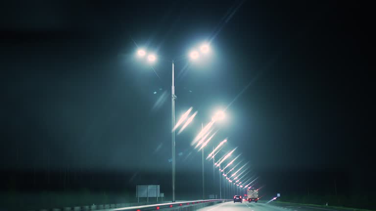 Driving a car at night in the fog along a highway illuminated by lanterns