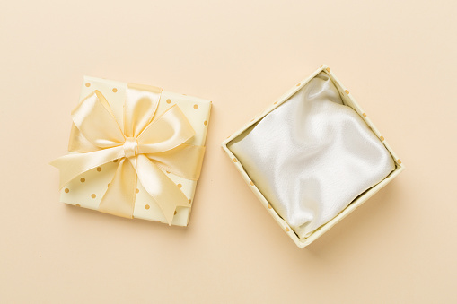 Beige open gift box on color background, top view