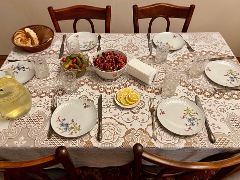 Bowls of beet salad, bread and pickles in the center of a dinner table covered with a crochet tablecloth and four place settings in a home in Tashkent, Uzbekistan