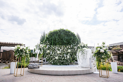 An elegant outdoor wedding photo zone with white bouquets of flowers and greenery..