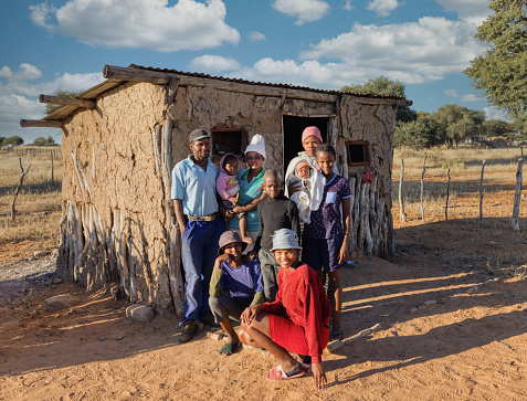 village, large african family standing in front of the mud house . late afternoon