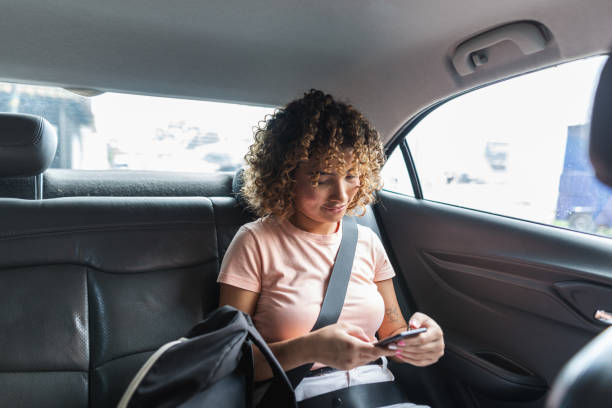 istock Female passenger using smartphone in the backseat of a car 2011500065