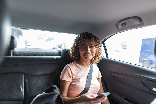 Female passenger using smartphone in the backseat of a car