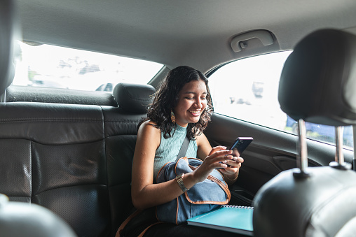 Female passenger using smartphone in the backseat of a car