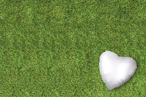 White heart balloon on a grass lawn