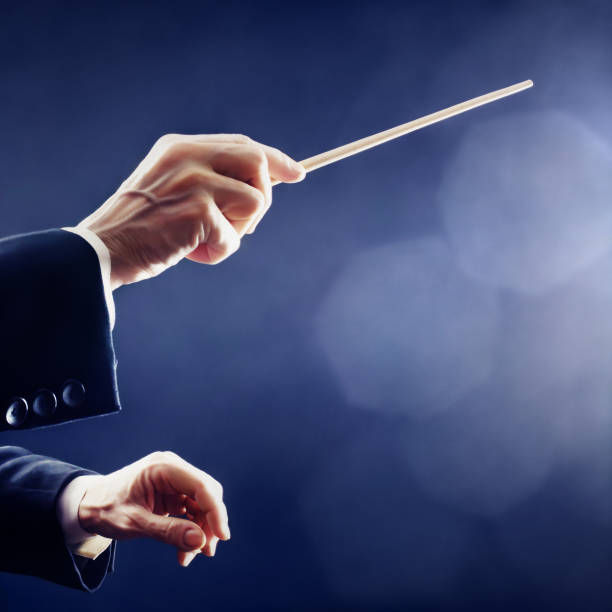 Music conductor hands with baton conducting symphony orchestra close up