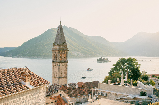 Bell tower of the Church of St. Nicholas against the background of the island of St. George in the Bay of Kotor. Perast, Montenegro. High quality photo