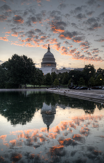 US Capitol at dawn with clouds reflected in the Capitol Reflecting Pool.