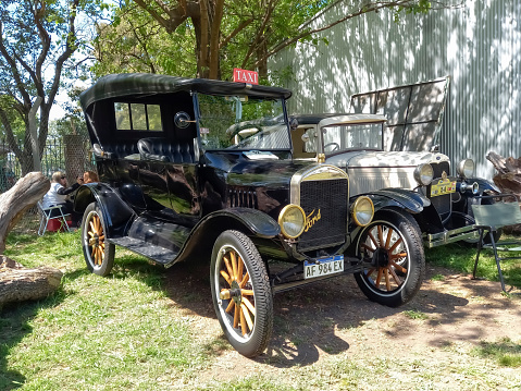 Remedios de Escalada, Argentina - Oct 8, 2023: Shot of a vintage black 1920s Ford Model T double phaeton taxi cab on the lawn at a classic car show in a park.