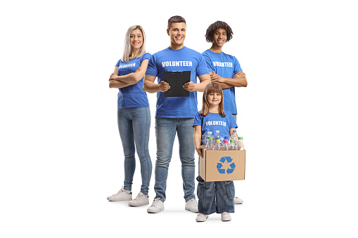 Group of adult volunteers in blue t-shirts and a child with a box of bottles for recycling isolated on white background