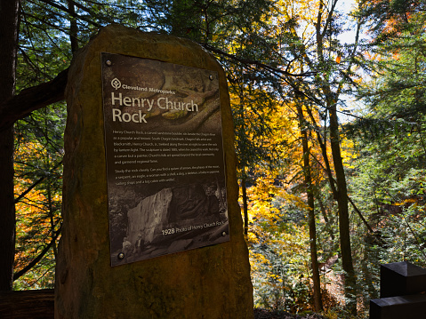 Bentleyville, OH, USA - October 24, 2023: An informational marker for the Henry Church Rock, a historic attraction in the South Chagrin Reservation, stands on the gorge rim above the rock itself.