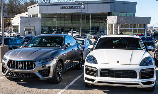 Wexford, Pennsylvania, USA February 4, 2024 A used Maserati and Porsche for sale at a dealership on a sunny winter day