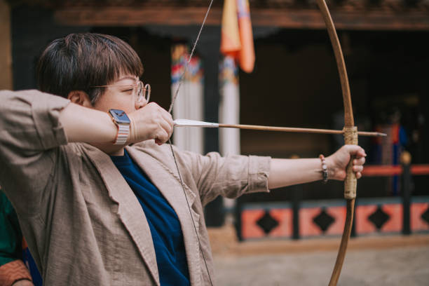Asian Chinese female tourist practicing archery aiming and shooting in field
