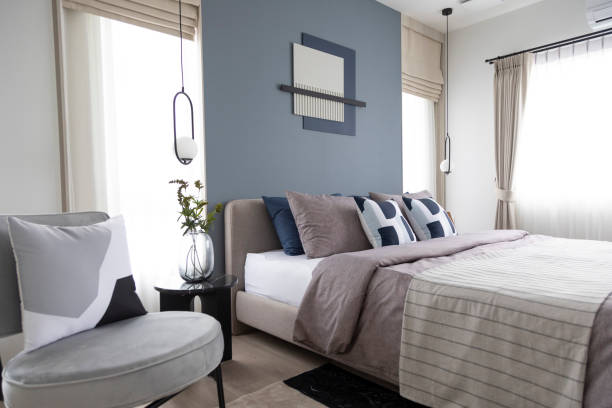 istock Stylish Bedroom with gray fabric headboard and bed with soft blue and white pillows 2011729497