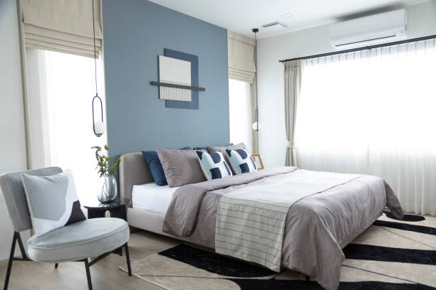 istock Stylish Bedroom with gray fabric headboard and bed with soft blue and white pillows 2011729500
