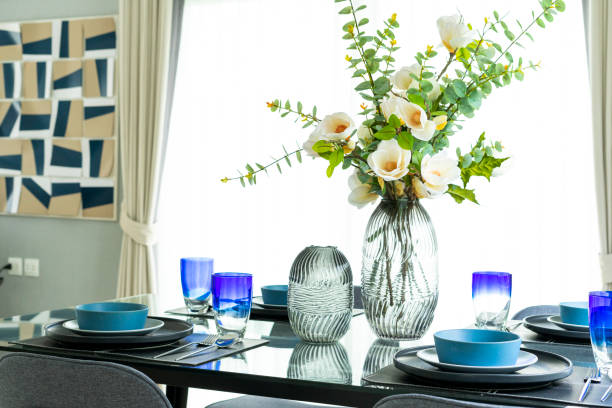 istock White flowers in vase on modern dinning table with blue plates. 2011729502