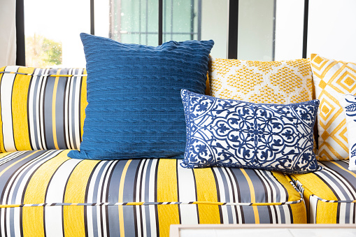 Stylish Mediterranean living room interior with bright yellow and blue sofa and pillow. Modern decor.