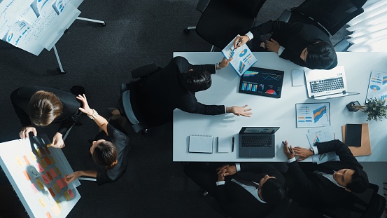 Top down view of professional business team working together to share idea while using colorful sticky note at whiteboard. Diverse project manager choosing or planning marketing strategy. Directorate.