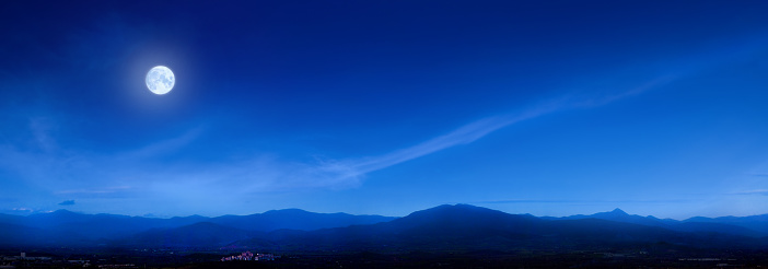 Dramatic view of the Moon in the twilight sky above the snowy mountain peaks of Norway, Scandinavia