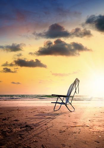 Single outdoor chair on sandy tropical beach during sunset in Sarasota, Florida