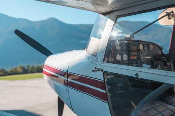Close-up view of a small plane's cockpit and propeller, with clear skies and mountains forming a serene backdrop, emphasizing the prospect of an aerial tour.