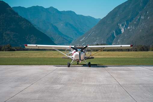A small aircraft on a tarmac, surrounded by scenic mountain landscape, ready for a panoramic flight experience.