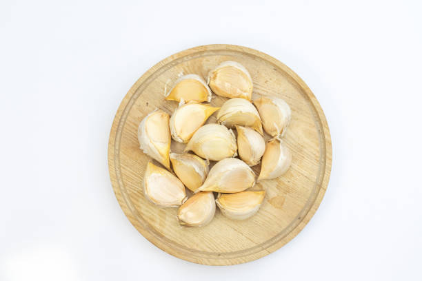 Garlic cloves on a wooden cutting board on white background with copy space