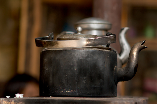 Worn metal teapot on the stove with a cluster of white rice, Bhutan