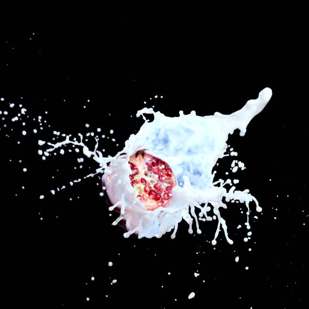Pomegranate splash in milk isolated on black background.