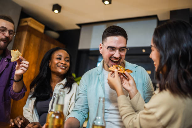 istock Multi-ethnic friends with pizza and bottles of drinks having party. 2011973007