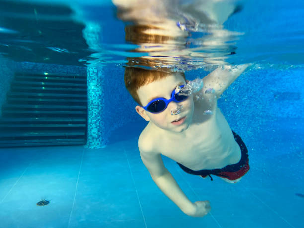 a boy swimming underwater in the pool - mobilestock freedom enjoyment blue стоковые фото и изображения
