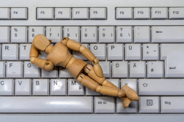 パソコンのキーボードの上で眠る木の人形