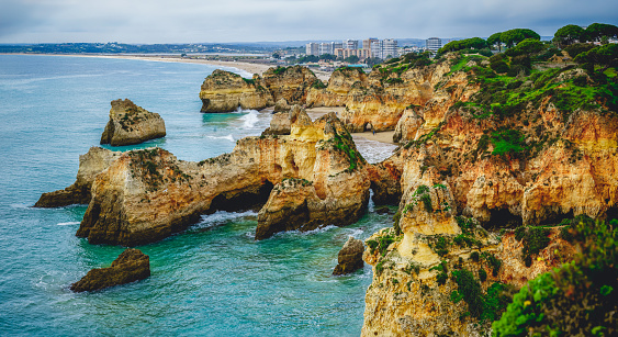 Panoramic view captures the rugged beauty of the Algarve's rocky coastline, where cliffs meet the crashing waves of the Atlantic Ocean.