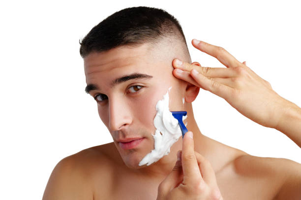 istock Young handsome man applying shaving foam against white background 2012044630