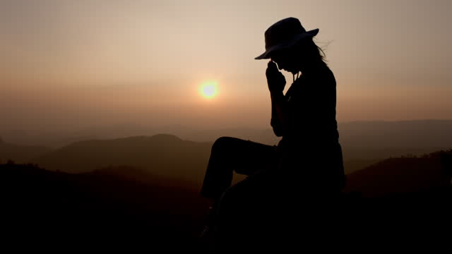 silhouette of a woman praying on the mountain, Praying hands with faith in religion and belief in God.