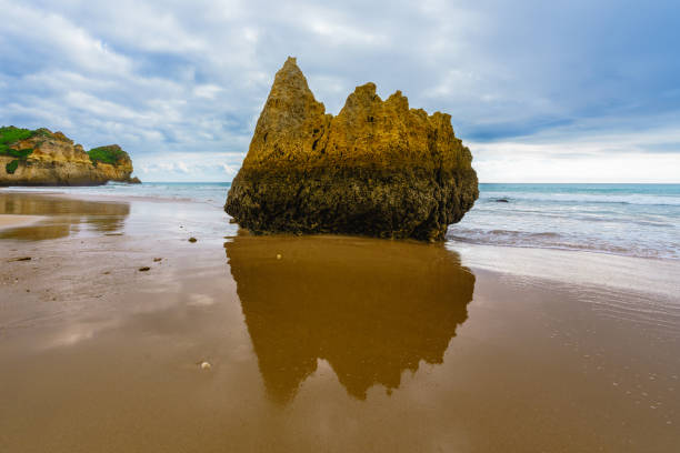 istock Rugged shoreline with rocky cliffs meeting a sandy beach under a dramatic overcast sky 2012050825