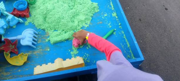 istock Hand scooping green kinetic sand. Educational toys for children. 2012084456