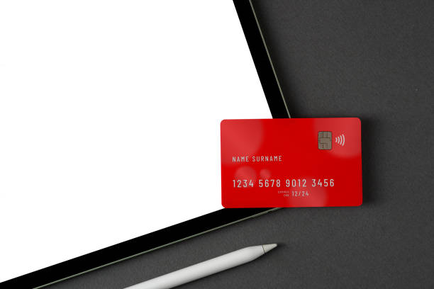 istock Credit card lying on tablet with blank screen on dark gray table 2012099484