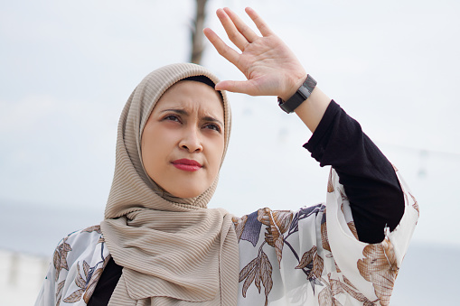 Radiant Indonesian Muslim Woman in Hijab dazzled by Sunlight on the Beach.