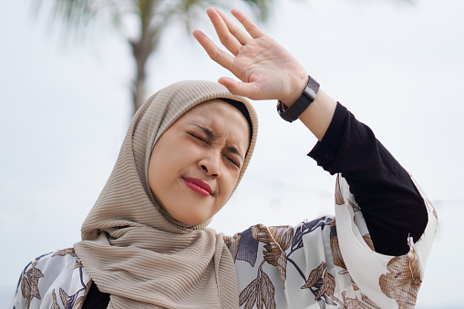 Radiant Indonesian Muslim Woman in Hijab dazzled by Sunlight on the Beach.