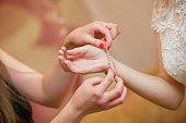 Women's hands put a bracelet on the bride's hand. A wedding or engagement.