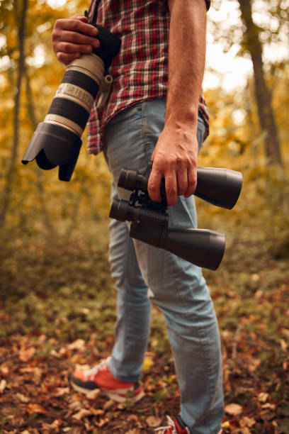 istock Man using binoculars and camera for birdwatching and other observing animals in nature. 2012194036