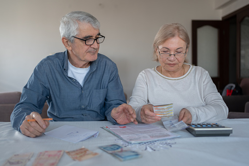 Senior Couple Calculating Bills And Expenses At Home