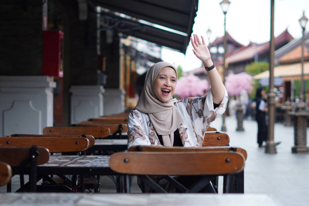 Activity Outdoor at the Beach. Outdoor activity concept, hijab woman outdoor Indonesian Hijabi Woman Waving at a Distance or Calling the Cafe Attendant or Calling her Friend summoning stock pictures, royalty-free photos & images