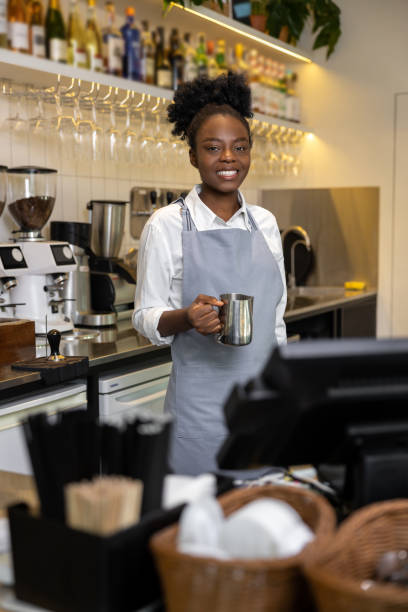 istock Smiling multicultural woman barista making coffee standing at counter in cafe 2012247597