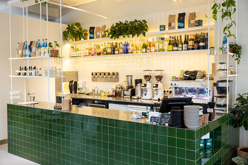 Interior of modern cafeteria with green bar counter shelves with drinks