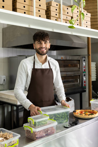 istock Handsome Caucasian bartender preparing pizza standing at counter in cafe kitchen 2012247630