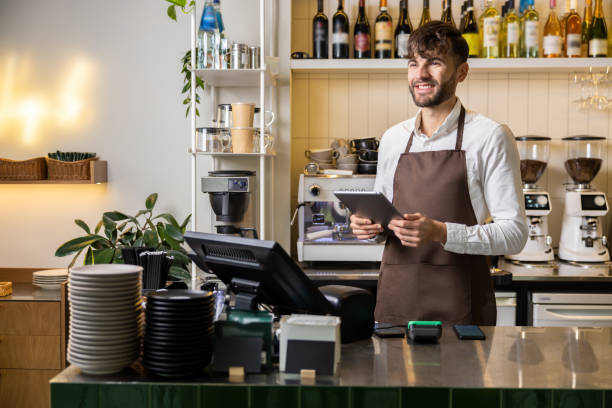 istock Man or waiter in apron with tablet pc computer at bar or coffee shop 2012248159