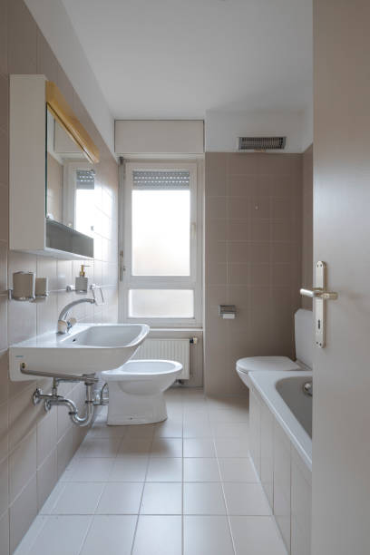 istock Front view of an old bathroom with tiles and a bright window. There is also a bathtub. 2012302812