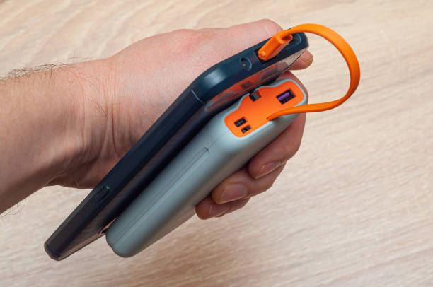 istock A phone charging via cable from a power bank holds a hand on a table background. Color gadget 2012306055